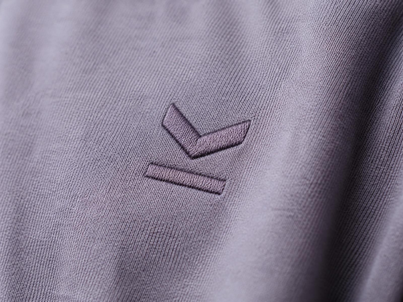 Détail macro du petit symbole brodé ton sur ton au niveau du cœur, côté gauche
