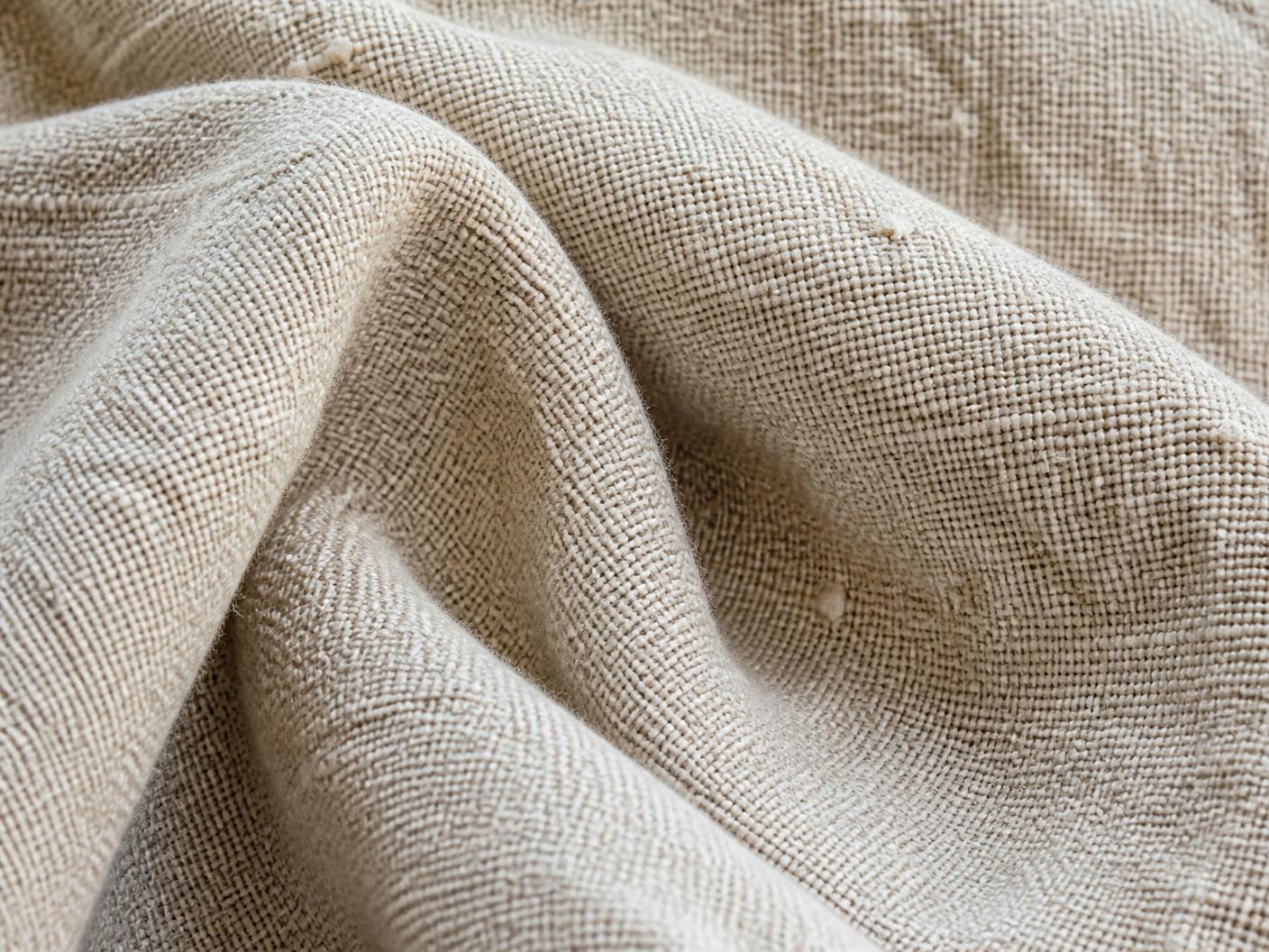 Macro d’un tissage de lin naturel à texture irrégulière, teinte avoine